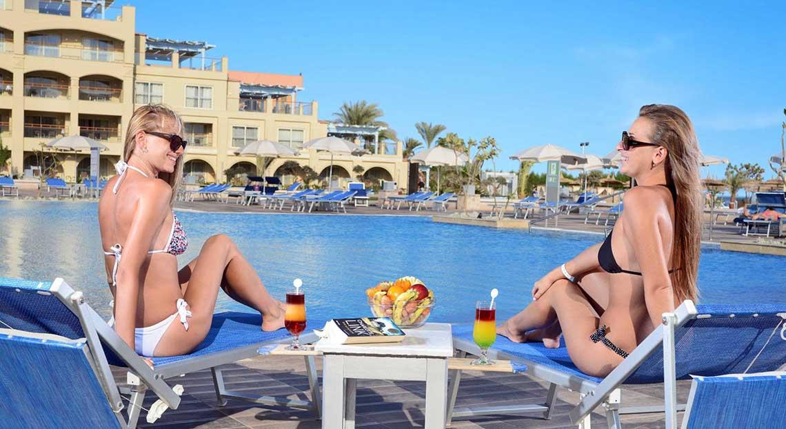 Zwei Frauen am Pool im Pickalbatros White Beach Resort, die Getränke genießen.