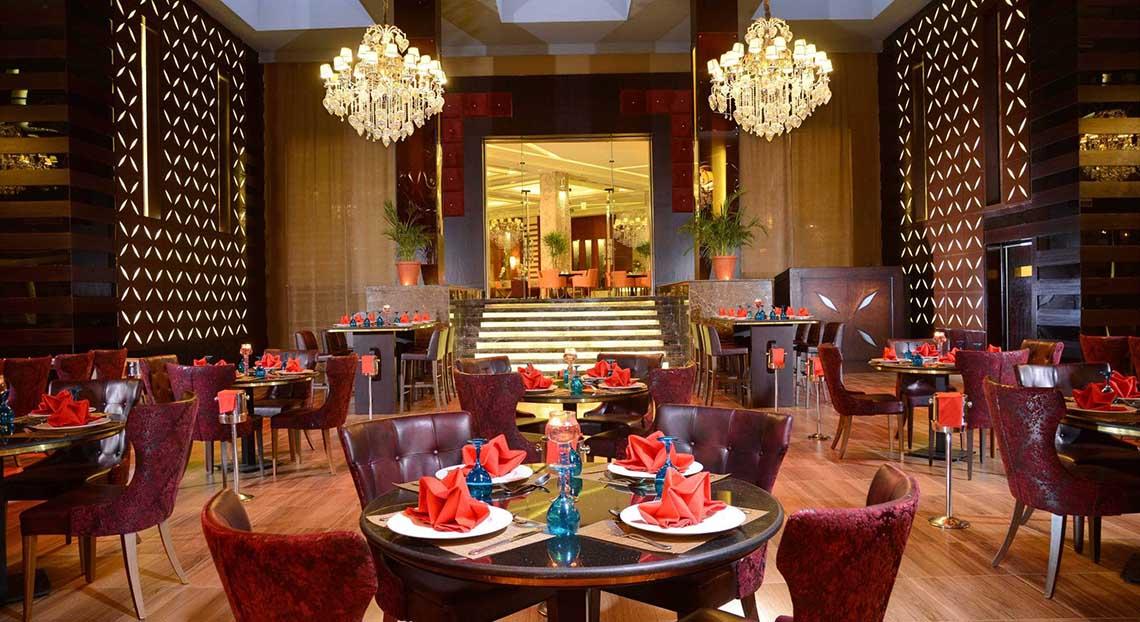 Innenansicht des Restaurants im Pickalbatros White Beach Resort mit geräumigen Tischen, luxuriösen Stühlen und großen Kronleuchtern.
