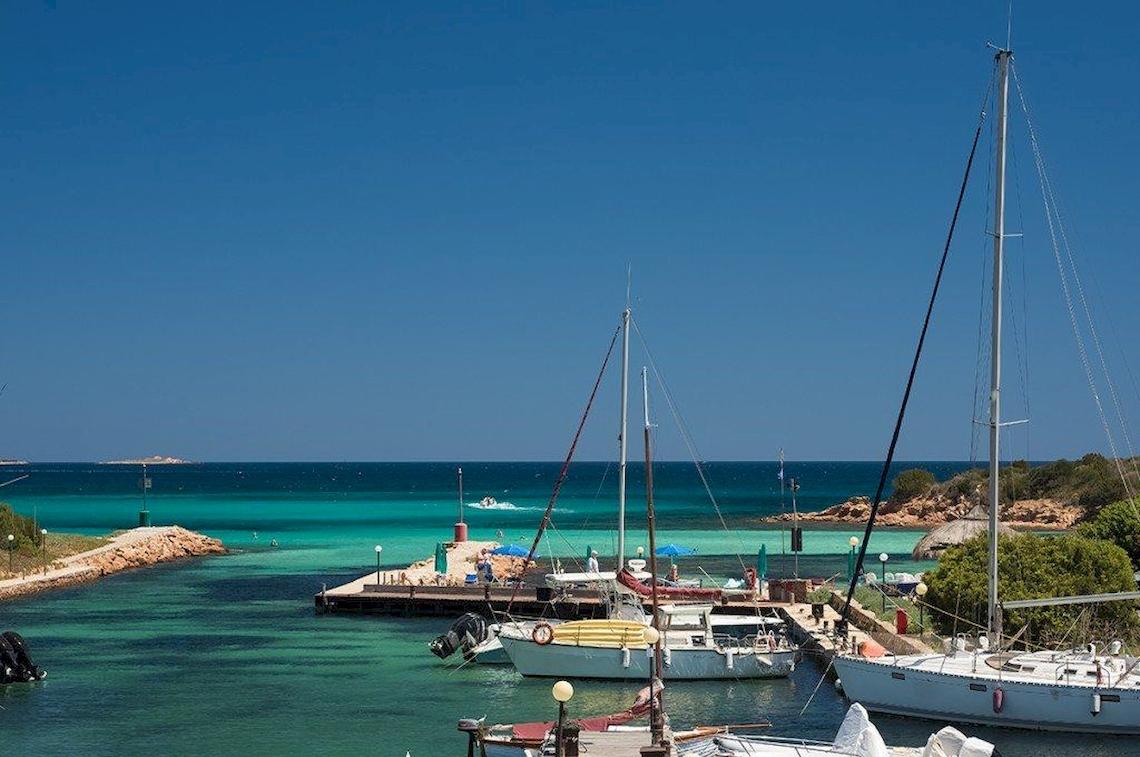 Foto von der Marina des Hotel Ollastu Resort mit mehreren Booten und türkisfarbenem Wasser.