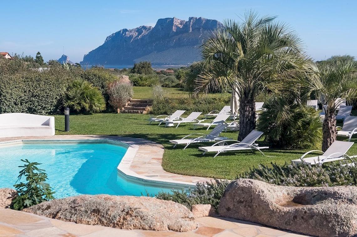 Außenbereich des Hotel Ollastu Resort mit Swimmingpool und Liegestühlen