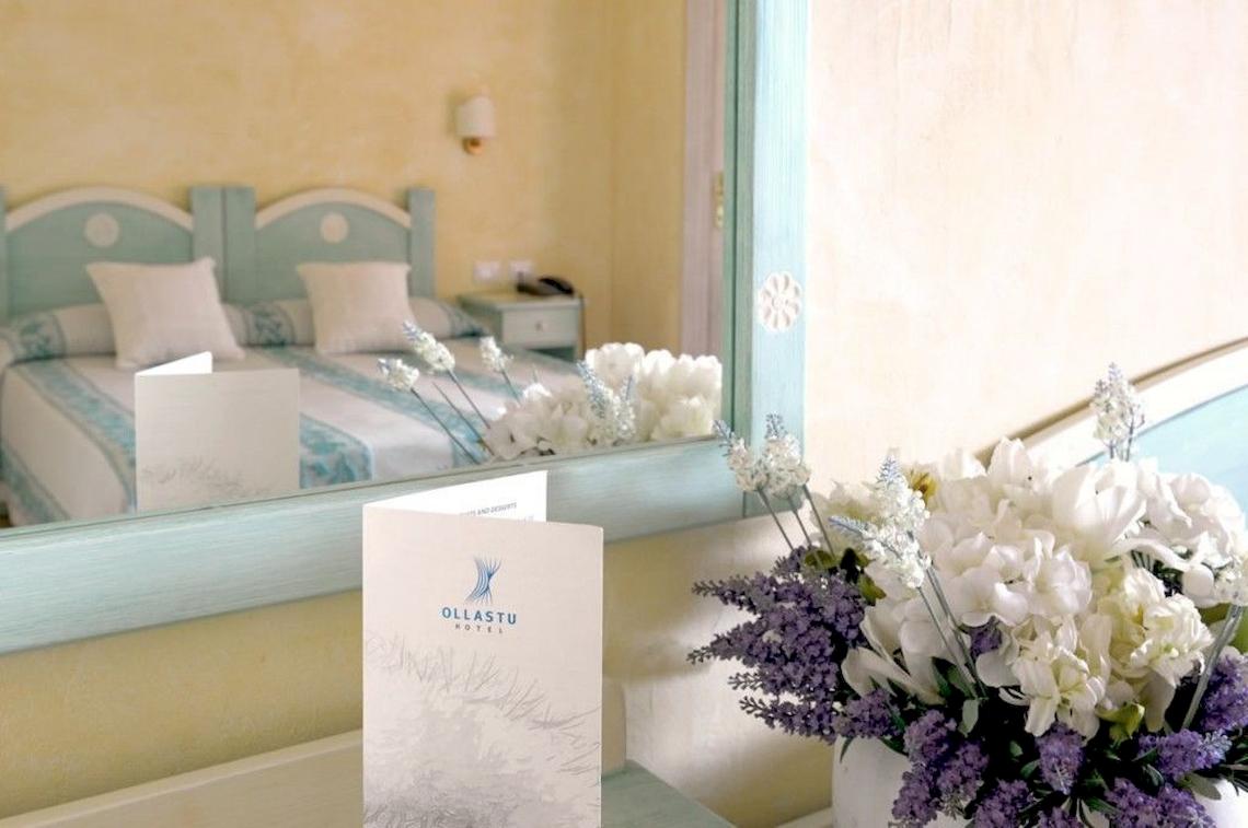 Ein Schlafzimmer mit Bett und Spiegel im Ollastu Resort Hotel.