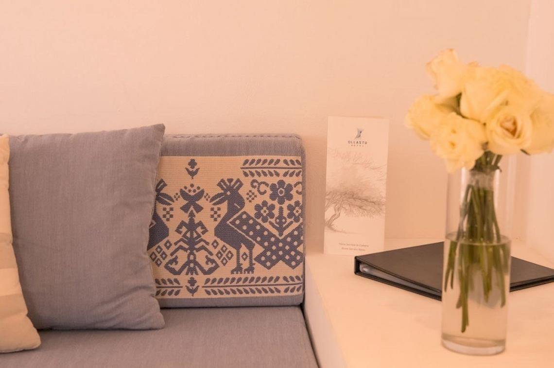 Inneneinrichtung des Hotel Ollastu Resort mit gepolstertem Sofa und gelben Rosen in Vase