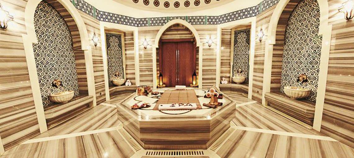 Innenansicht des Spas im Rixos The Palm Hotel & Suites mit Marmorwänden und einem zentralen Bad.