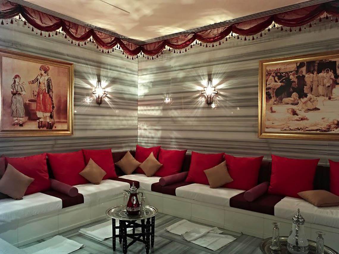Innenbereich des Rixos The Palm Hotel & Suites mit einem weißen Sofa, roten Kissen und zwei Gemälden an der Wand.