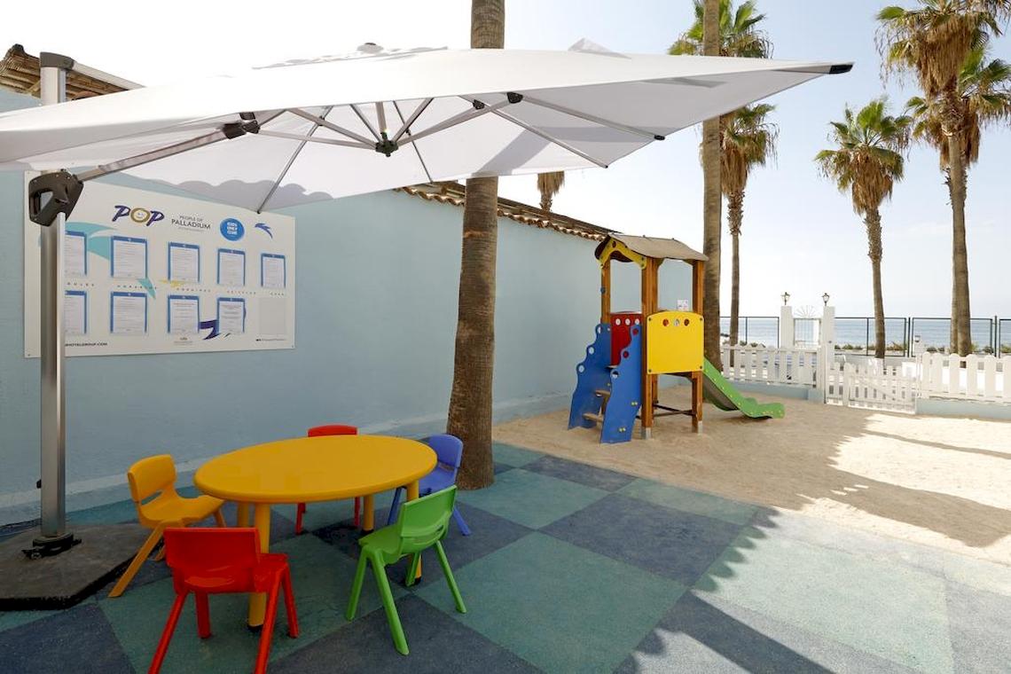 Kinderspielplatz des Playabonita Hotels mit bunten Stühlen, Tisch und Spielgeräten.
