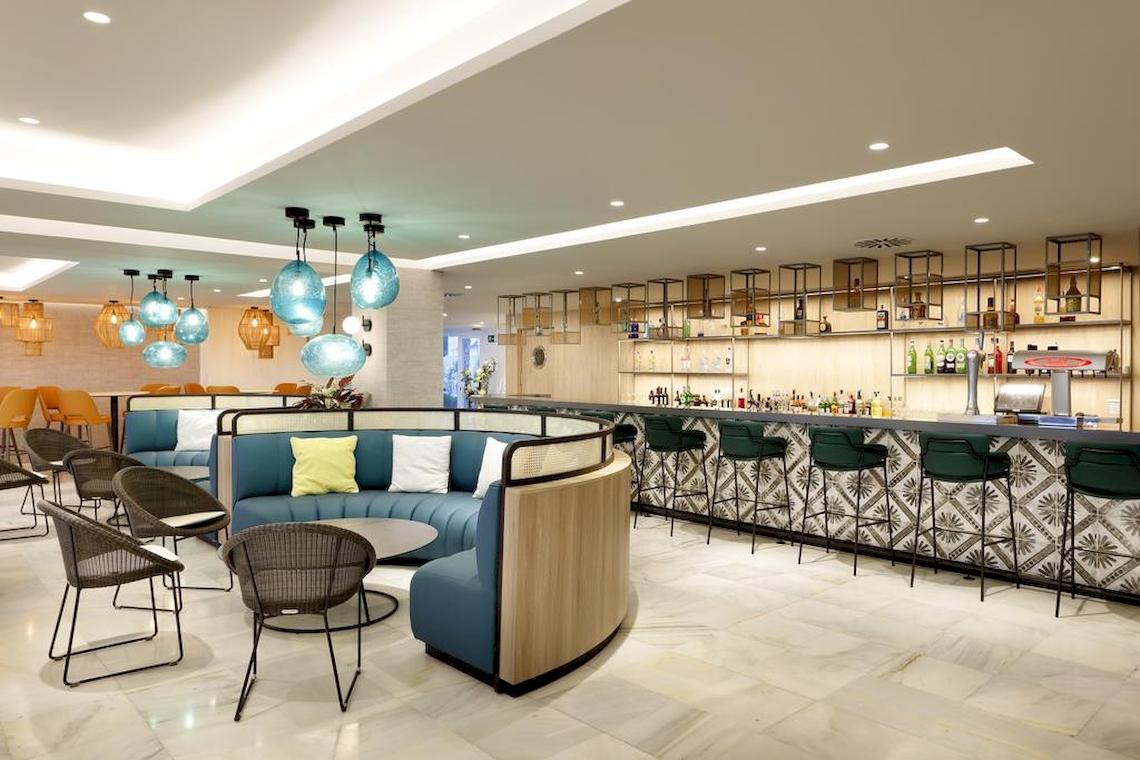 Die Bar-Lounge im Playabonita Hotel mit blauen Sitzbereichen und grünen Hockern.