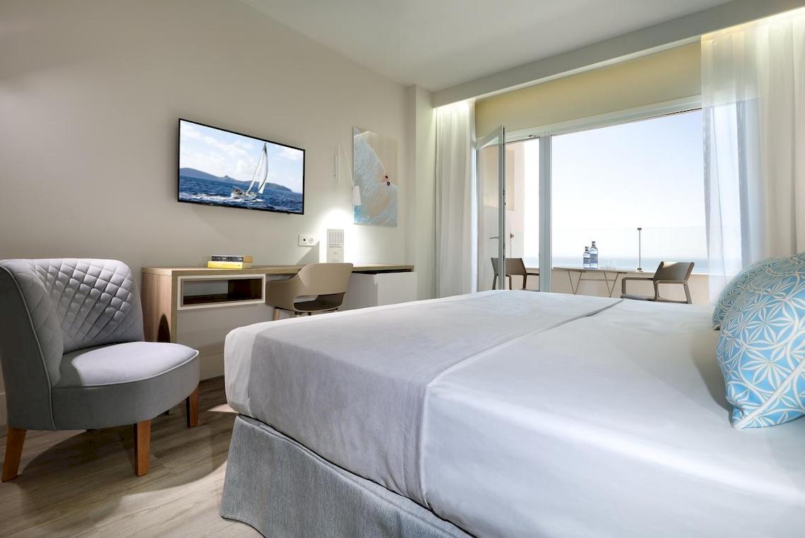 Innenansicht eines Zimmers im Playabonita Hotel mit Bett, Schreibtisch und Fernseher.