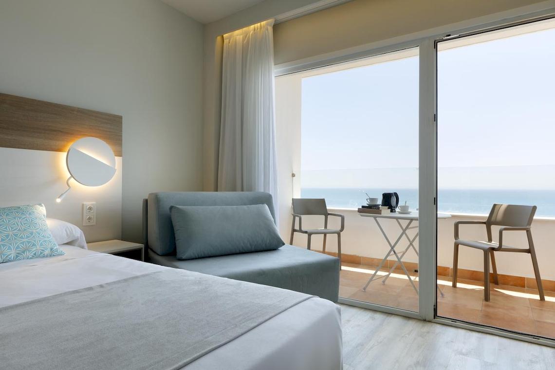 Playabonita Hotel Zimmer mit Meerblick und Balkon, Bett, Sofa und Esstisch.