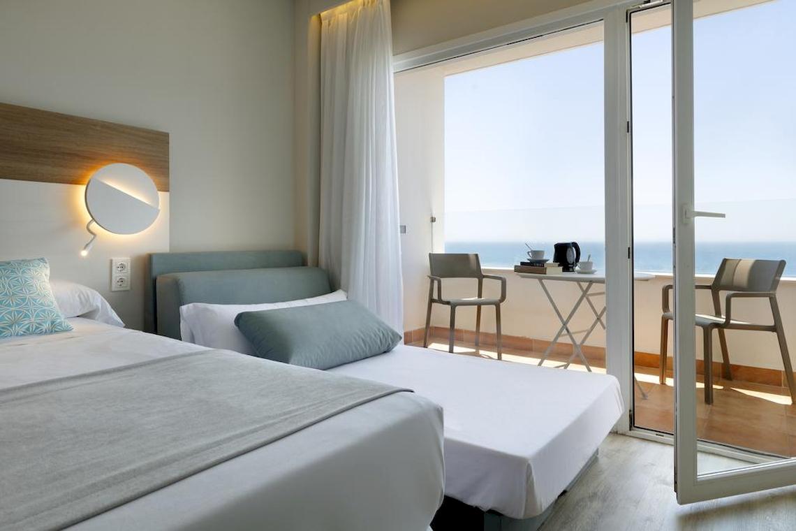 Doppelzimmer im Playabonita Hotel mit Meerblick, zwei Betten, einem Tisch und Stühlen auf dem Balkon.