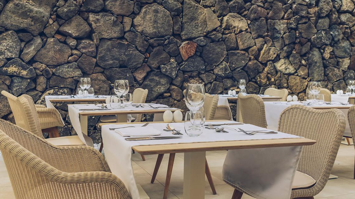 Innenansicht des Restaurants im Iberostar Selection Fuerteventura Palace mit Steinwand und gedeckten Tischen.