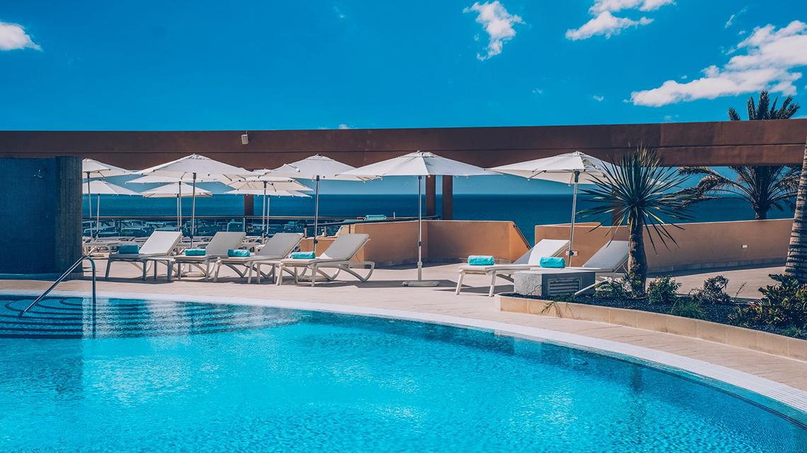 Pool-Terrasse des Iberostar Selection Fuerteventura Palace mit Lounge-Sesseln und Sonnenschirmen.