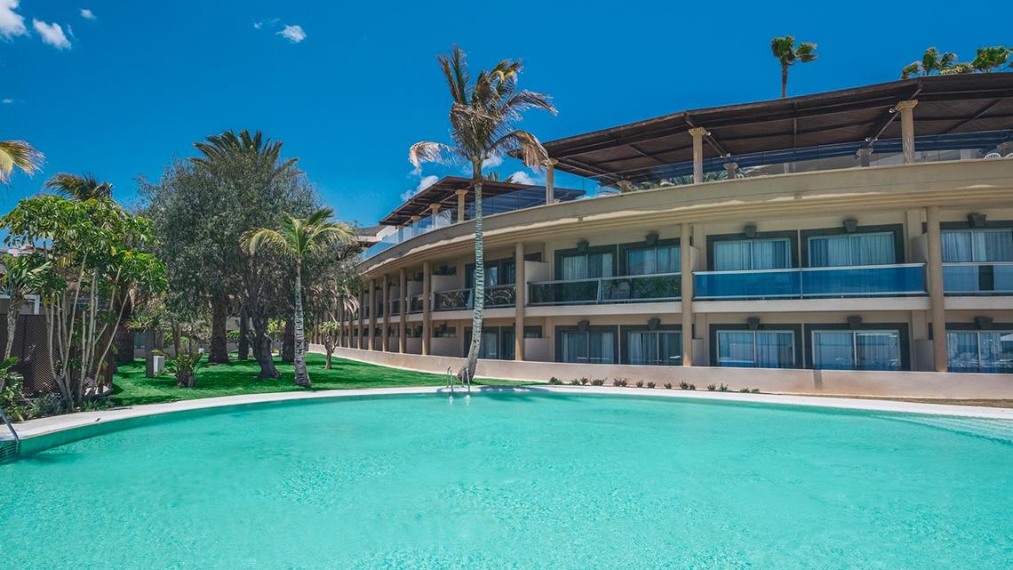 Außenansicht des Iberostar Selection Fuerteventura Palace Hotels mit Pool und tropischen Bäumen.