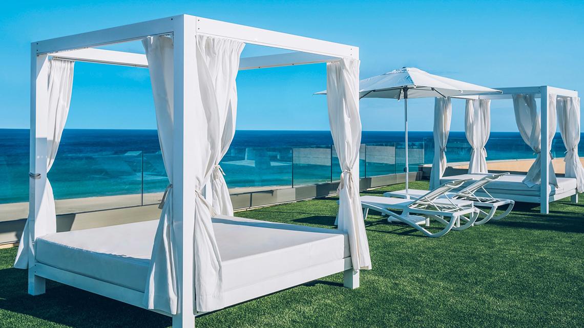 Poolside-Lounge-Bereich im Iberostar Selection Fuerteventura Palace mit weißen Liegen und Sonnenschirmen.