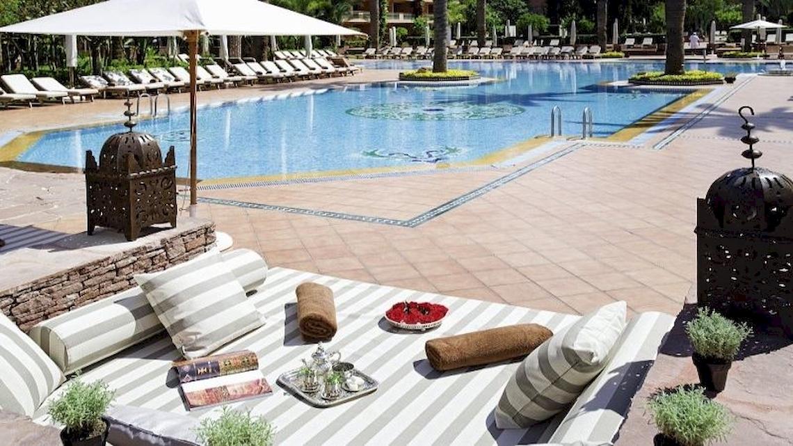 Außenbereich des Sofitel Marrakech Lounge & Spa Hotels mit einem großen Pool und Liegestühlen.
