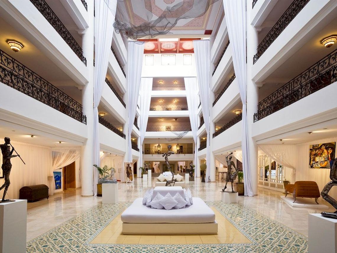 Innenansicht des Sofitel Marrakech Lounge mit weißen Vorhängen, Marmorboden und Kunstwerken.