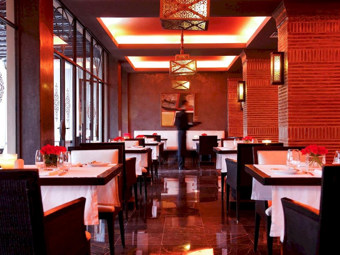 Innenansicht des Sofitel Marrakech Lounge & Spa Restaurants mit roten Leuchten und gedeckten Tischen.