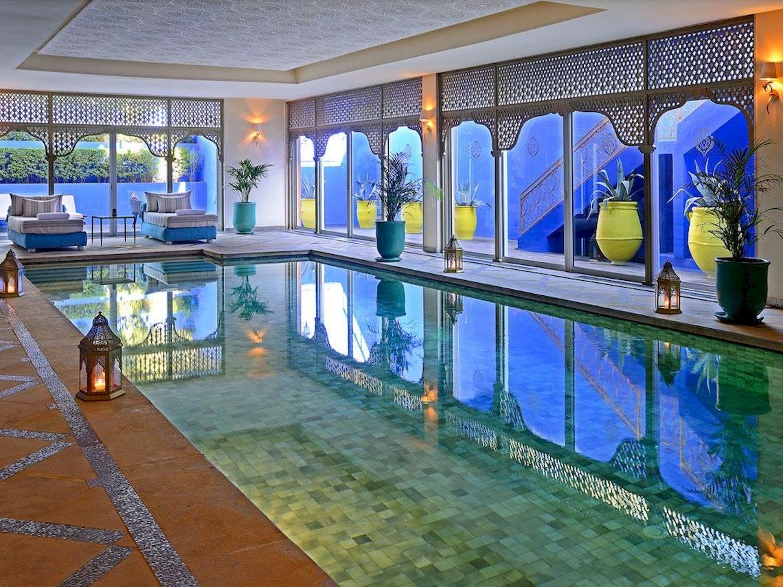 Pool im Sofitel Marrakech Lounge & Spa mit blauen Wänden und grünen Pflanzen.