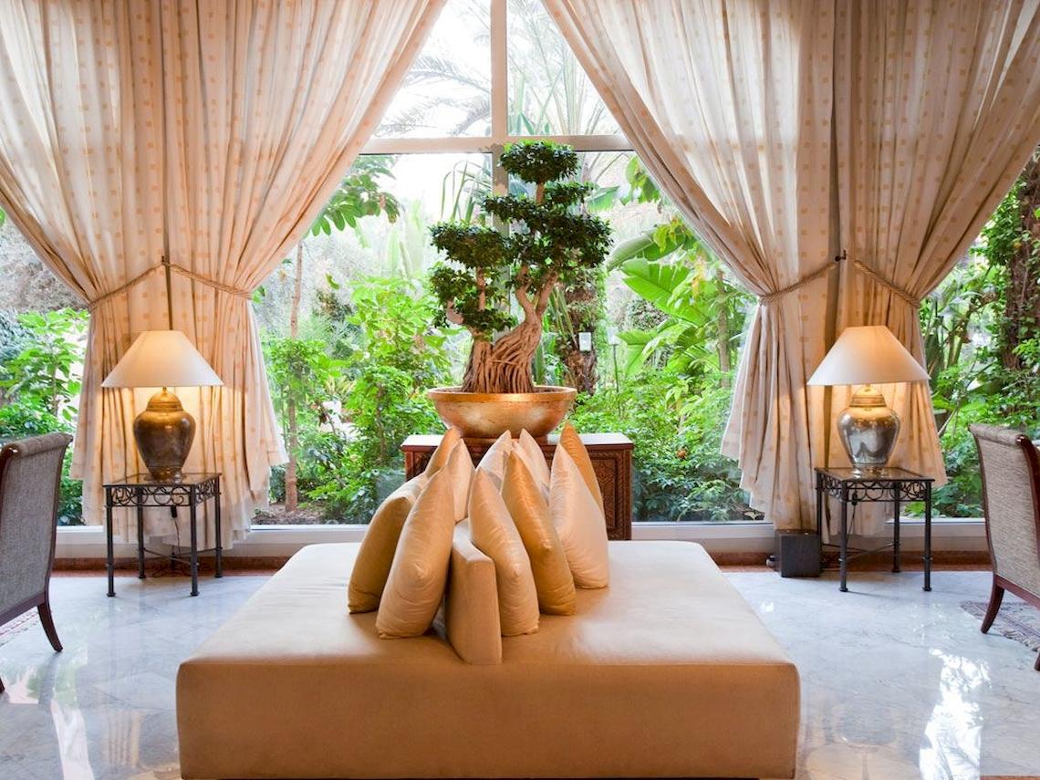 Sofa mit Kissen vor einem großen Fenster im Sofitel Marrakech Lounge & Spa Hotel.
