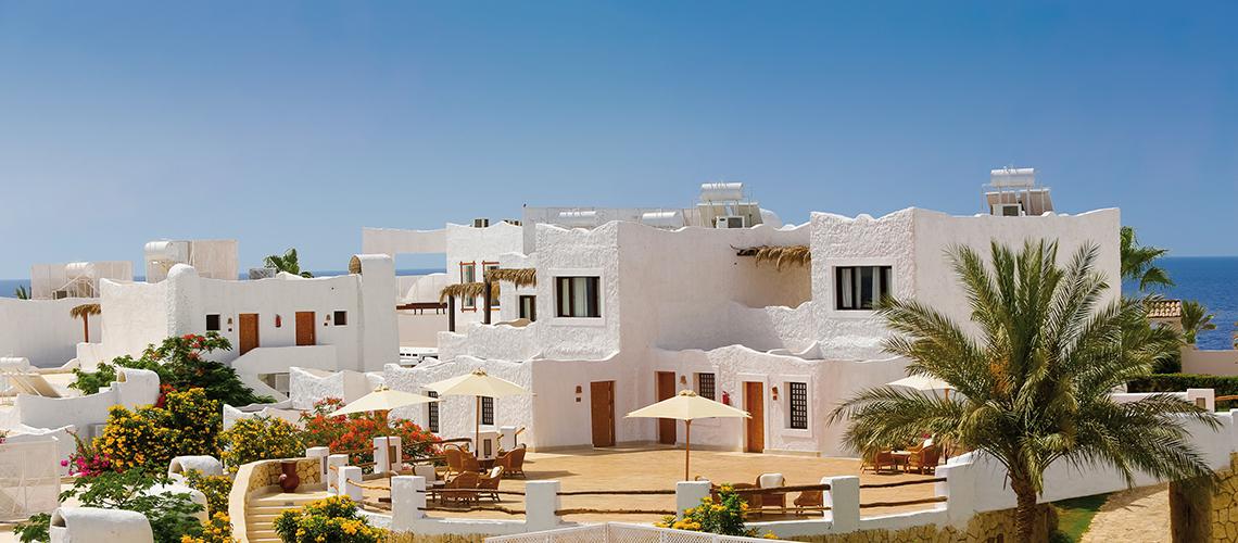 Außenbereich des Sharm Club Beach Resorts mit weißen Gebäuden und Palmen