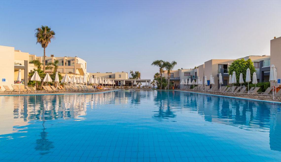 Außenpool des Callisto Holiday Village mit Sonnenliegen und Sonnenschirmen