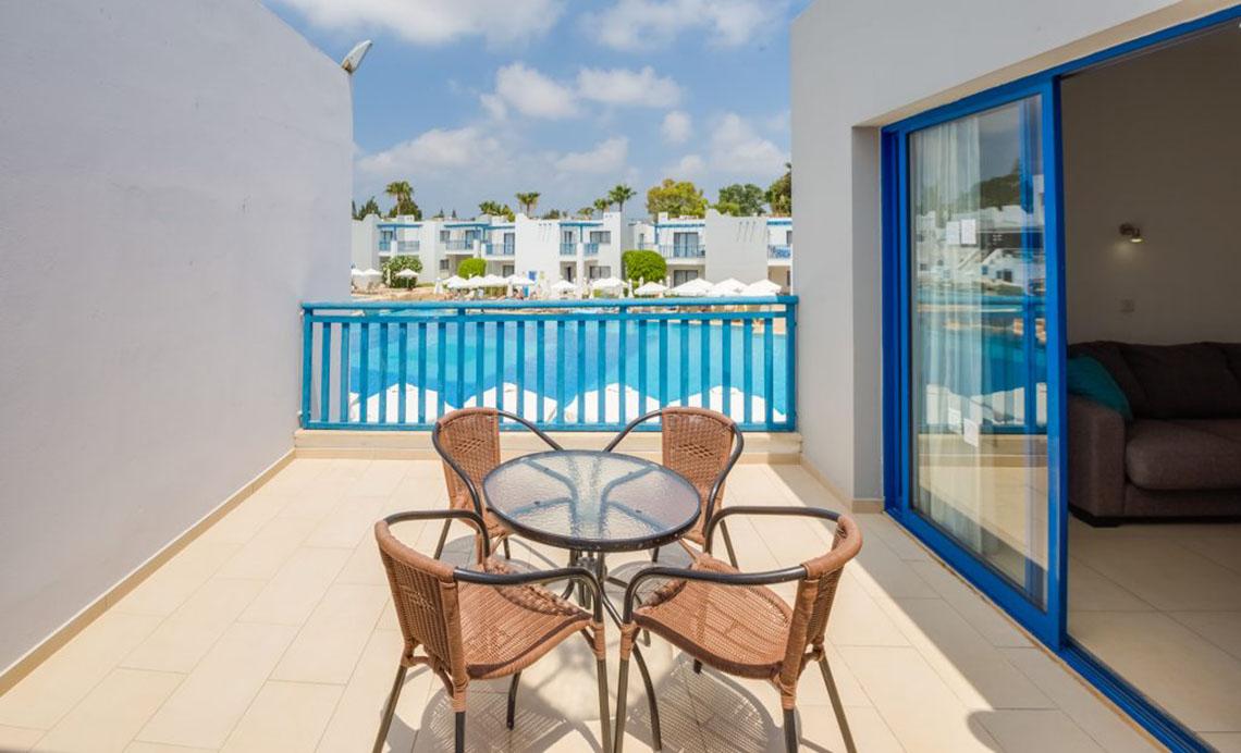 Balkon im Callisto Holiday Village mit Tisch und Stühlen, Blick auf den Pool.