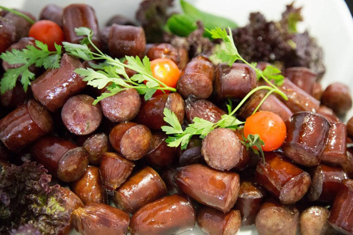 Nahaufnahme von gegrillten Würstchen mit Tomaten und Petersilie