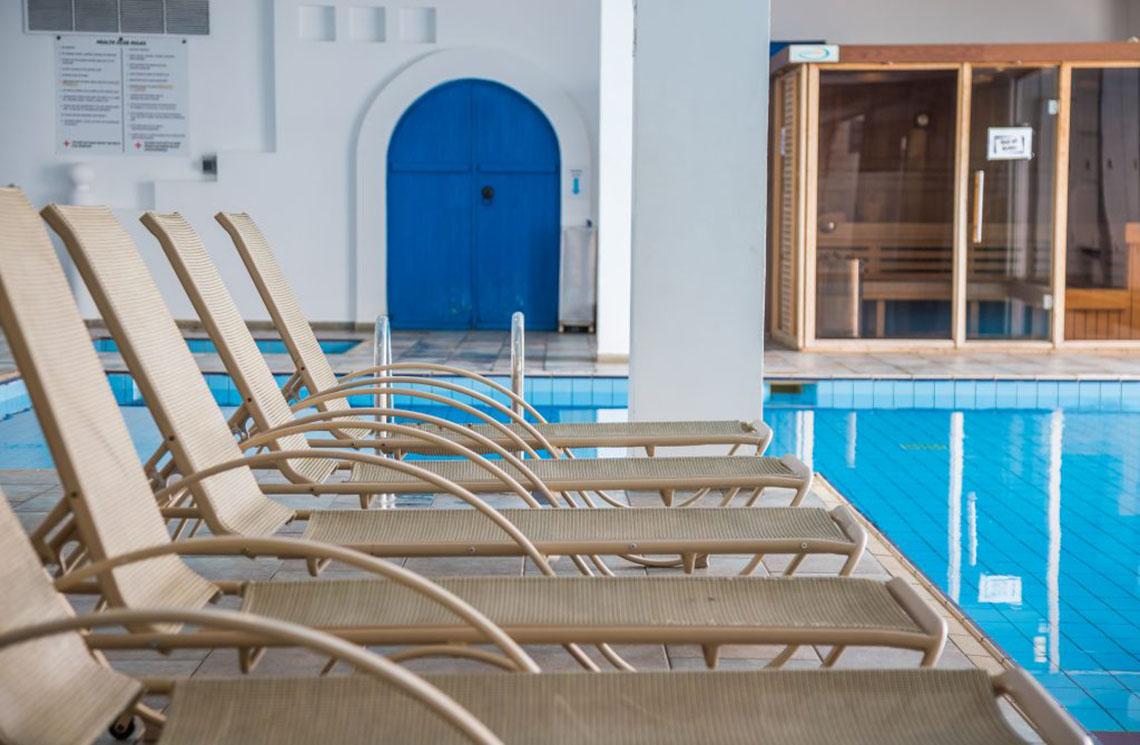 Reihe von Liegestühlen neben dem Pool im Callisto Holiday Village