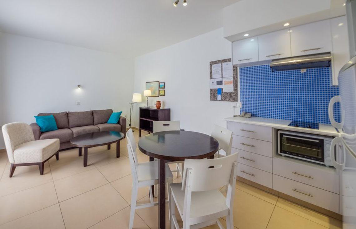 Wohnbereich im Callisto Holiday Village mit Couch, Tisch und Küche.