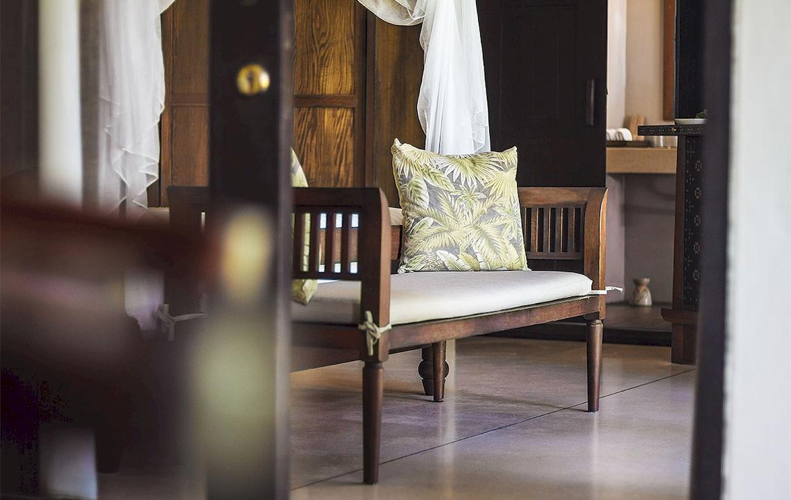 Sitzbank im Saree Samui Resort mit Kissen und Vorhängen.