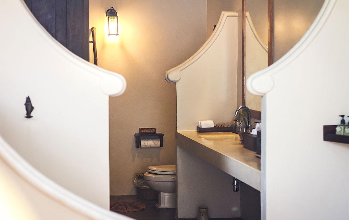 Ein Badezimmer im Saree Samui Resort mit einer Toilette, einem Waschbecken und einer Lampe.