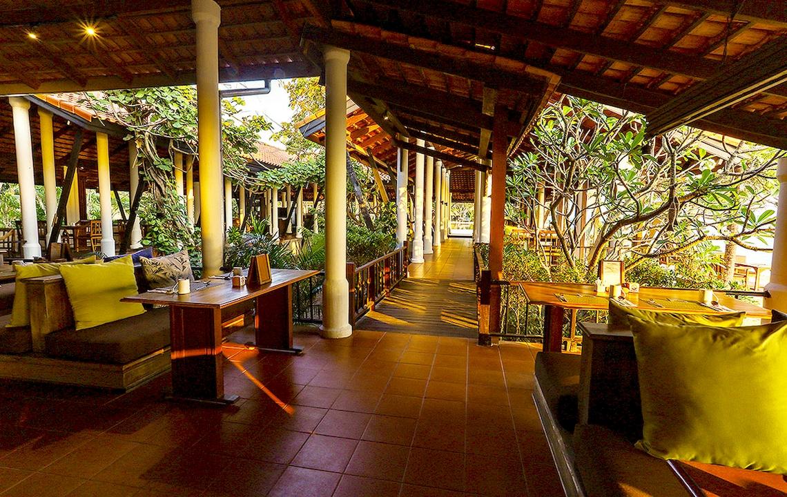 Außenbereich des Saree Samui Resorts mit gelben Kissen und Holztischen.