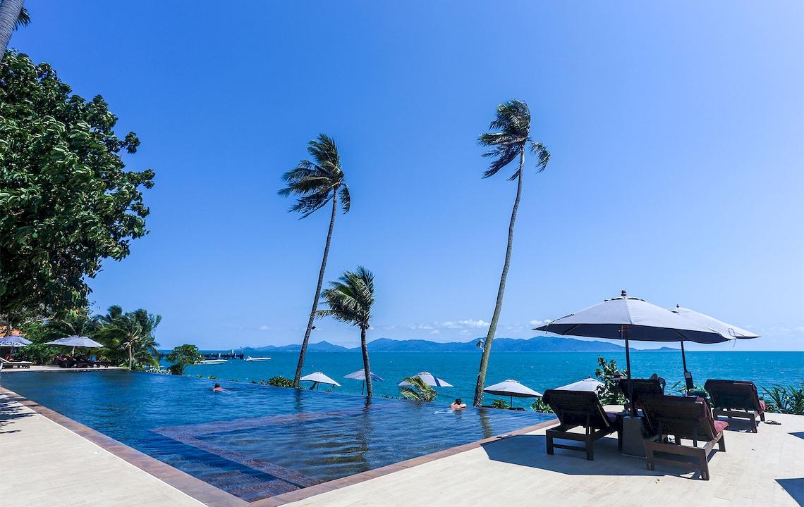 Außenpool des Saree Samui Resorts mit zwei Personen im Wasser und Sonnenschirmen.