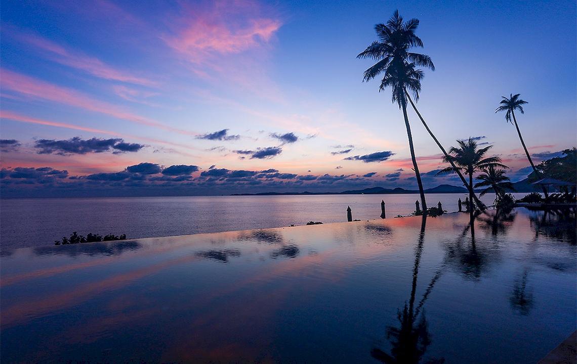 Sunset am Pool des Saree Samui Resorts mit Palmen und Meer im Hintergrund