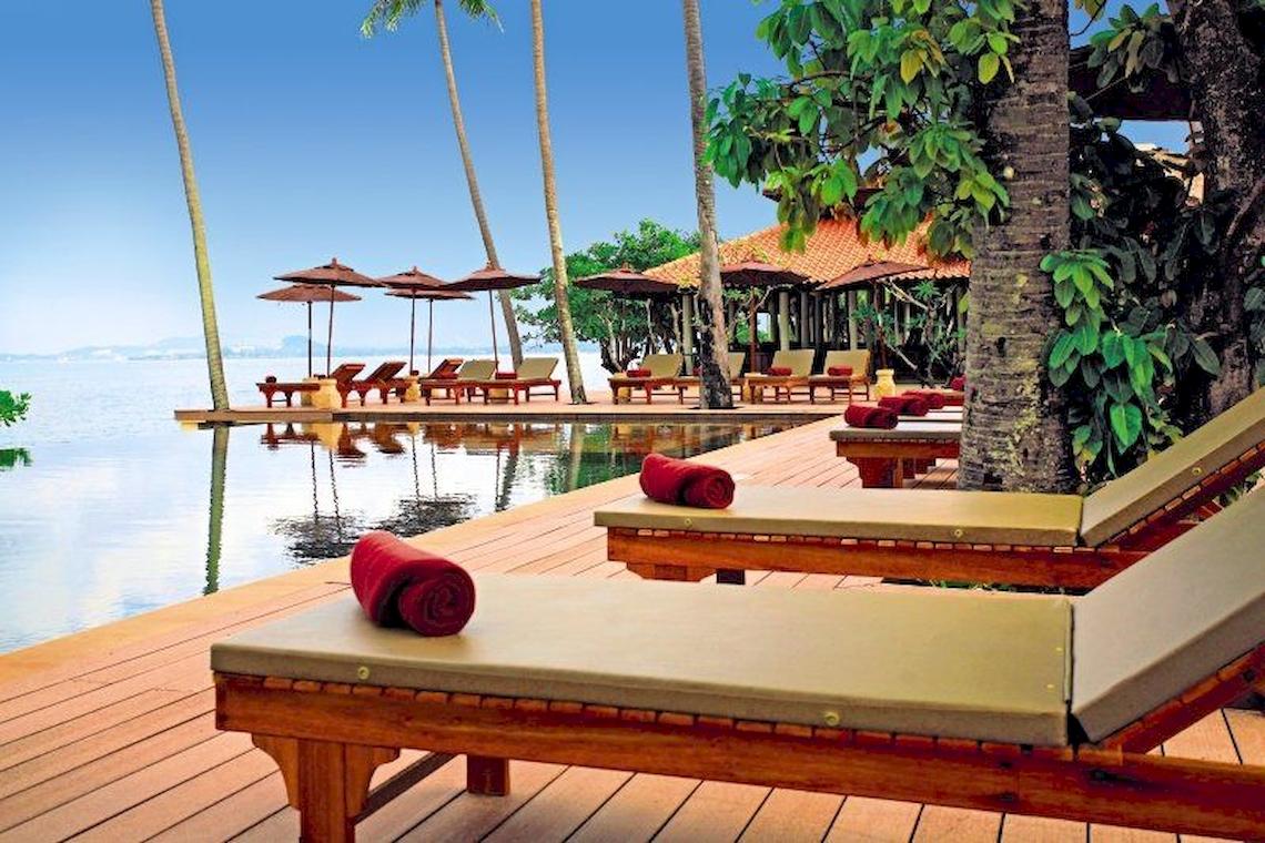 Außenbereich des Saree Samui Resorts mit Loungeliegen und einem Pool am Meer