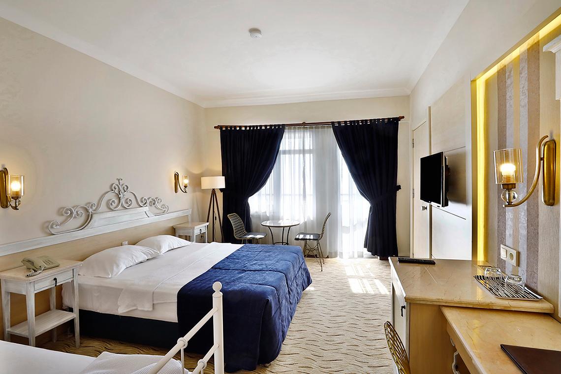 Schlafzimmer im Club Yali Hotels & Resort mit zwei Betten, Schreibtisch und Fernseher.