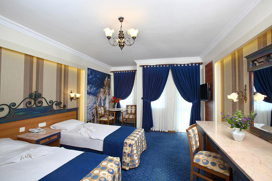 Doppelzimmer im Club Yali Hotels & Resort mit zwei Betten, Schreibtisch, Stühlen und einem Fernseher.