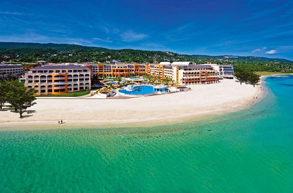 Luftaufnahme des Iberostar Selection Rose Hall Suites Hotels am Strand mit Swimmingpools und blauem Wasser.