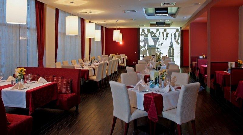 Innenansicht des Restaurants des Sol Nessebar Palace All Inclusive Hotels mit roten Möbeln und Dekoration.