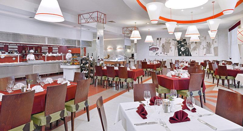 Innenansicht des Restaurants im Sol Nessebar Palace Hotel mit gedeckten Tischen und kochenden Köchen.