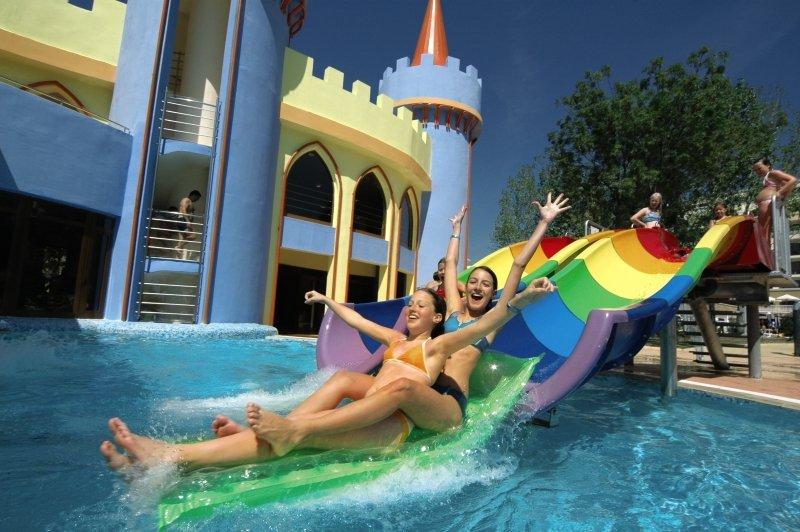 Zwei Frauen rutschen auf einer farbenfrohen Wasserrutsche im Wasserpark des Sol Nessebar Palace.