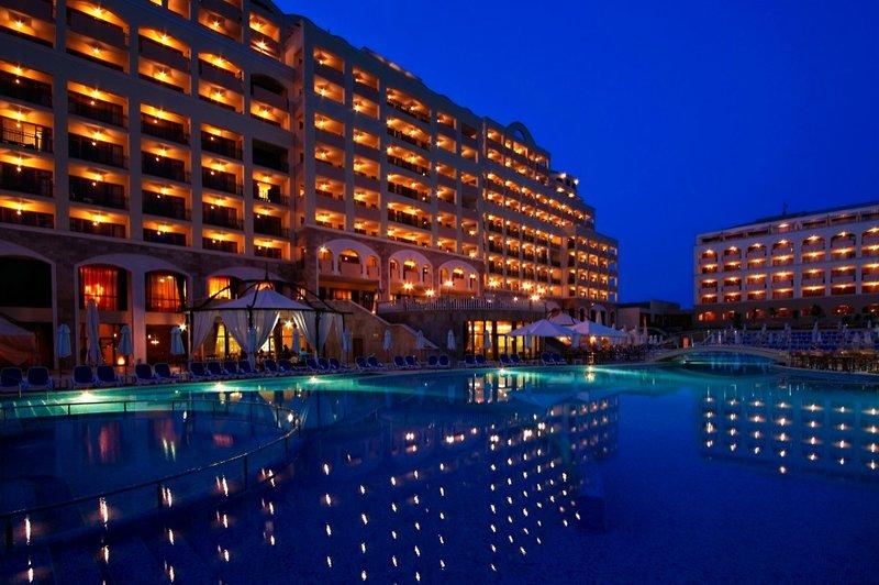 Nachtansicht des Sol Nessebar Palace All Inclusive Hotels mit beleuchtetem Pool und Loungebereich.