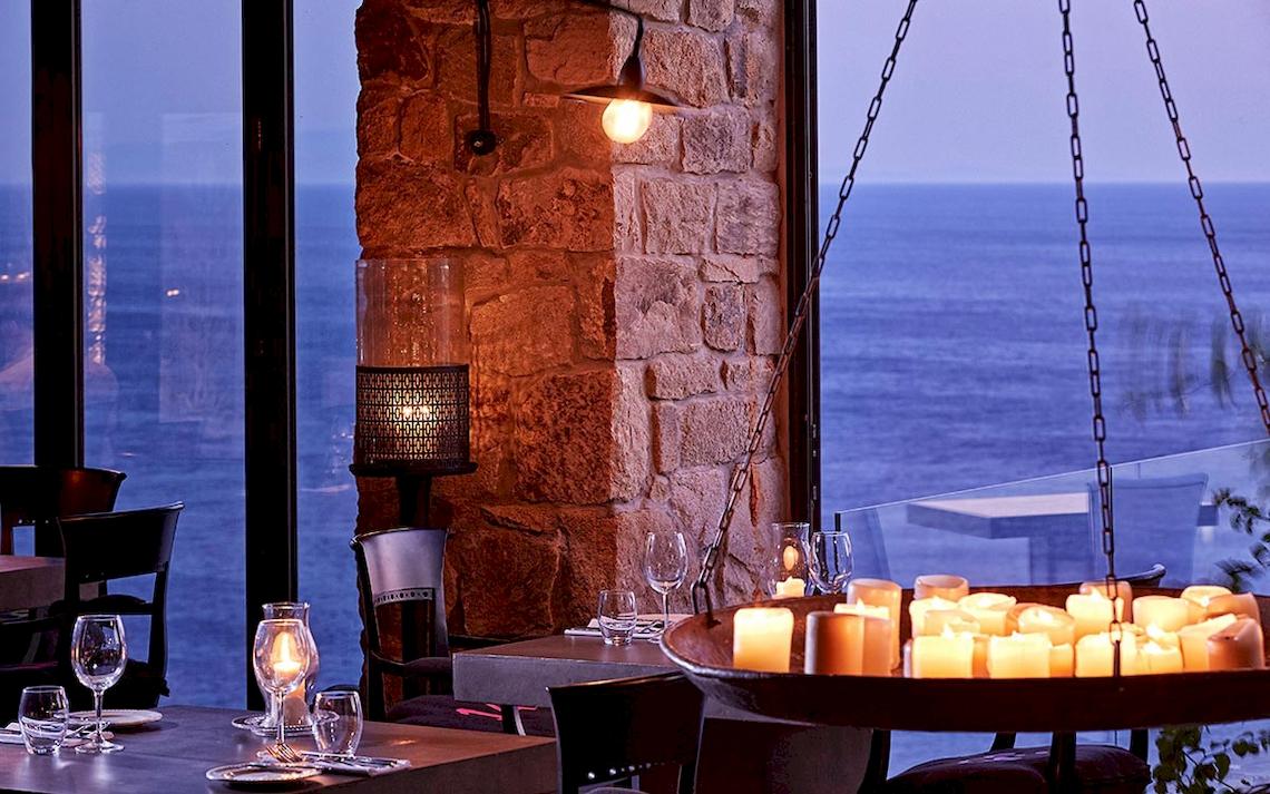 Innenansicht des Restaurants im Royal Myconian Resort mit Blick auf das Meer.