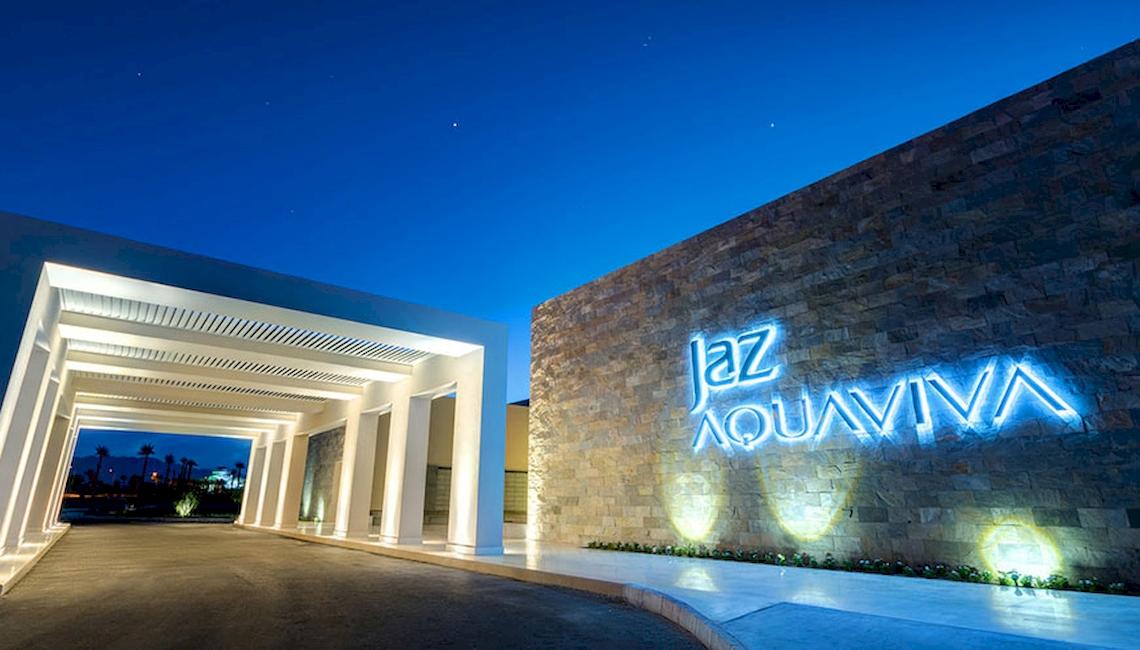 Die Beleuchtung des Jaz Aquaviva Hotels bei Nacht, mit dem Hotelnamen auf einer Wand.