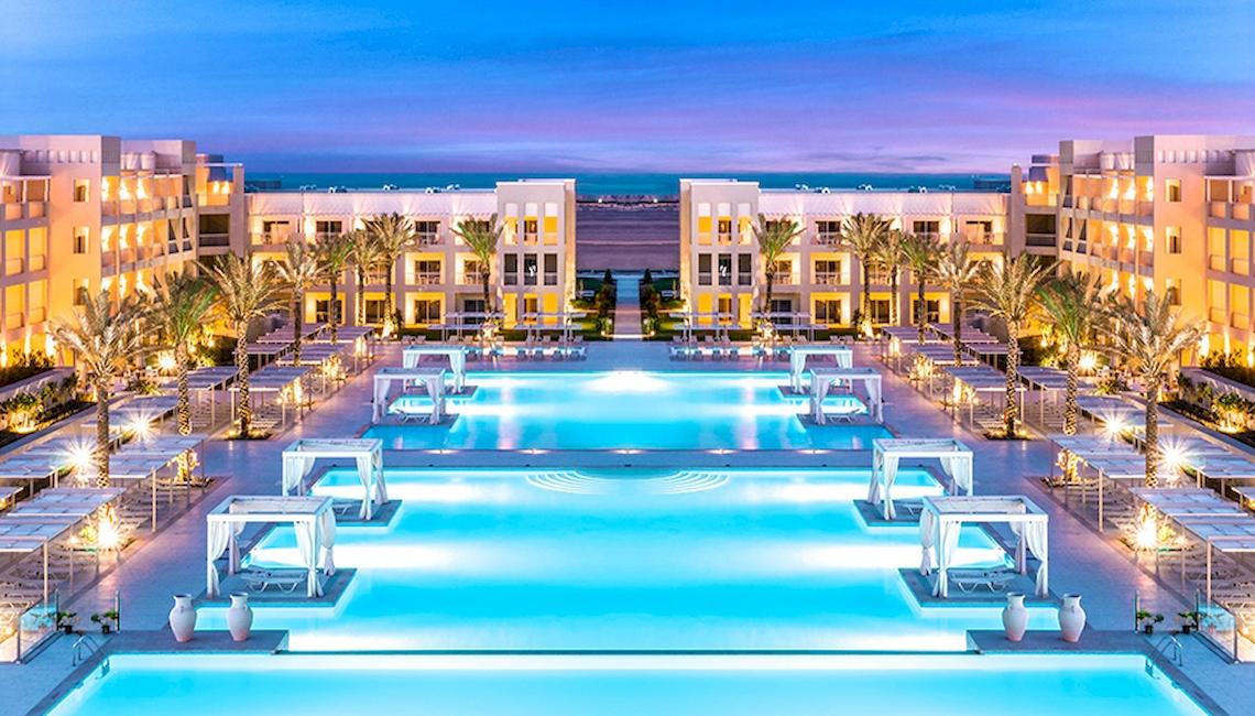 Jaz Aquaviva Hotel Pool Ansicht mit beleuchteten Gebäuden und Palmen bei Nacht