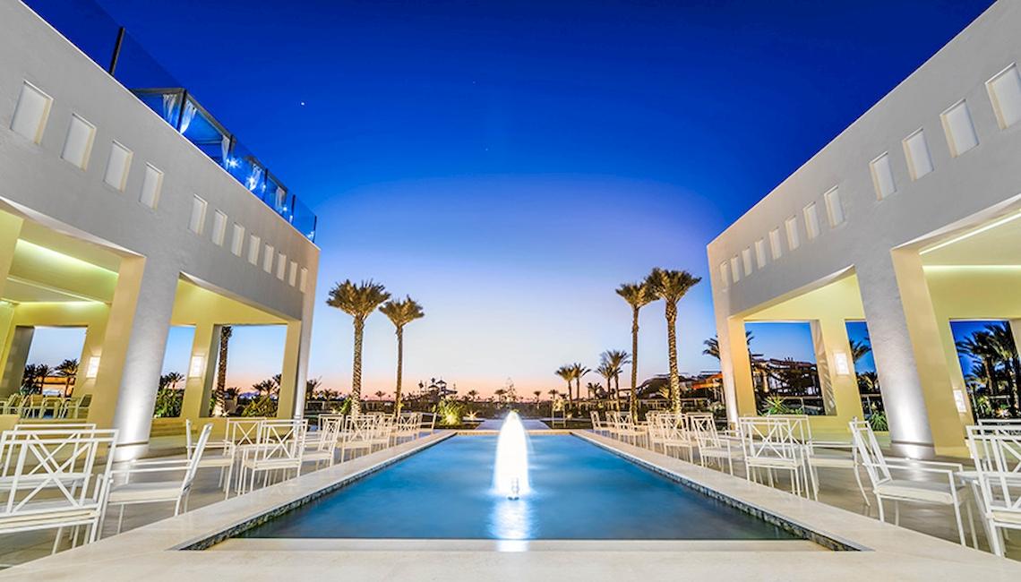 Außenbereich des Jaz Aquaviva Hotels mit einem Brunnen und weißen Stühlen bei Nacht.