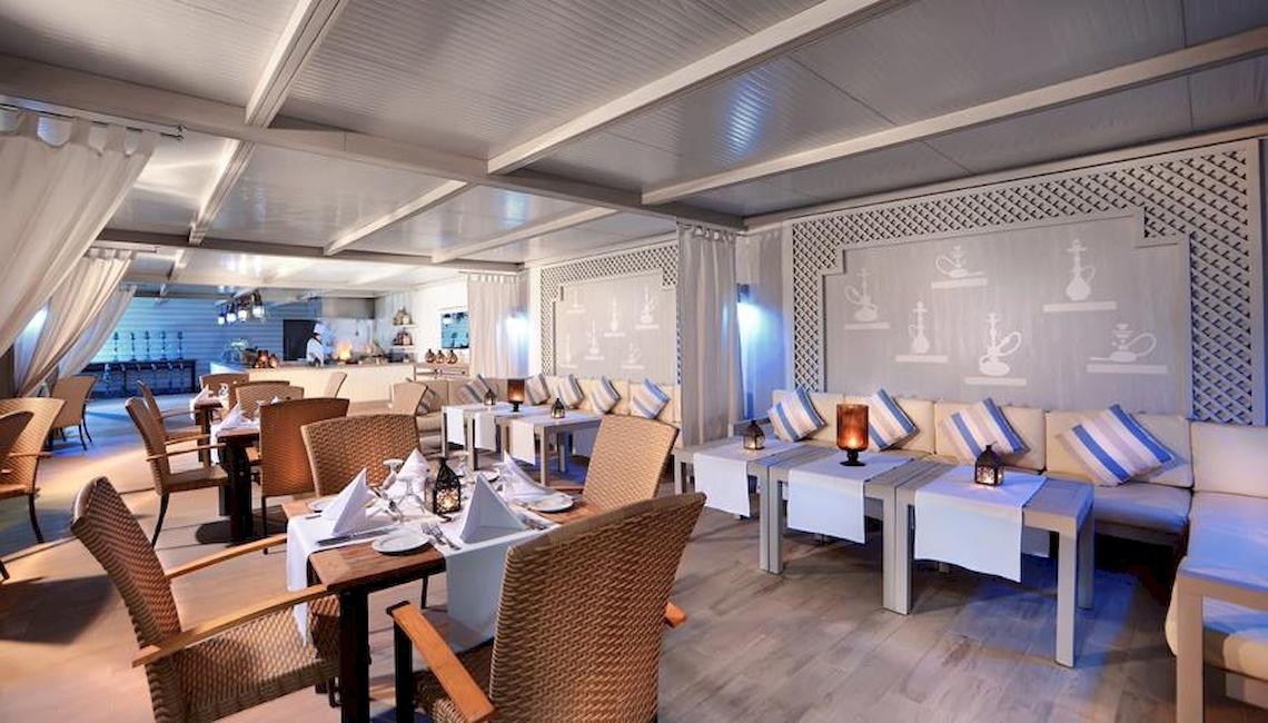Innenbereich des Jaz Aquaviva Hotels mit Tischen, Stühlen und weißen Möbeln.