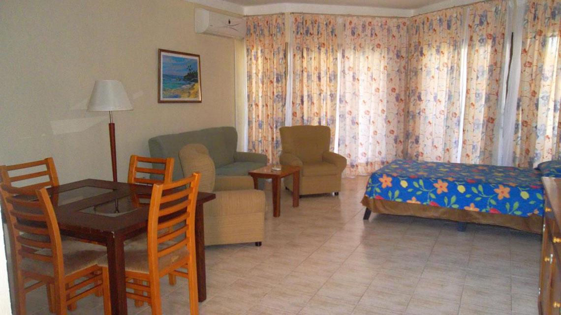 Ein Hotelzimmer mit Tisch, Stühlen, Couch, Sessel, Lampe und Bett im Roc Arenas Doradas Hotel.