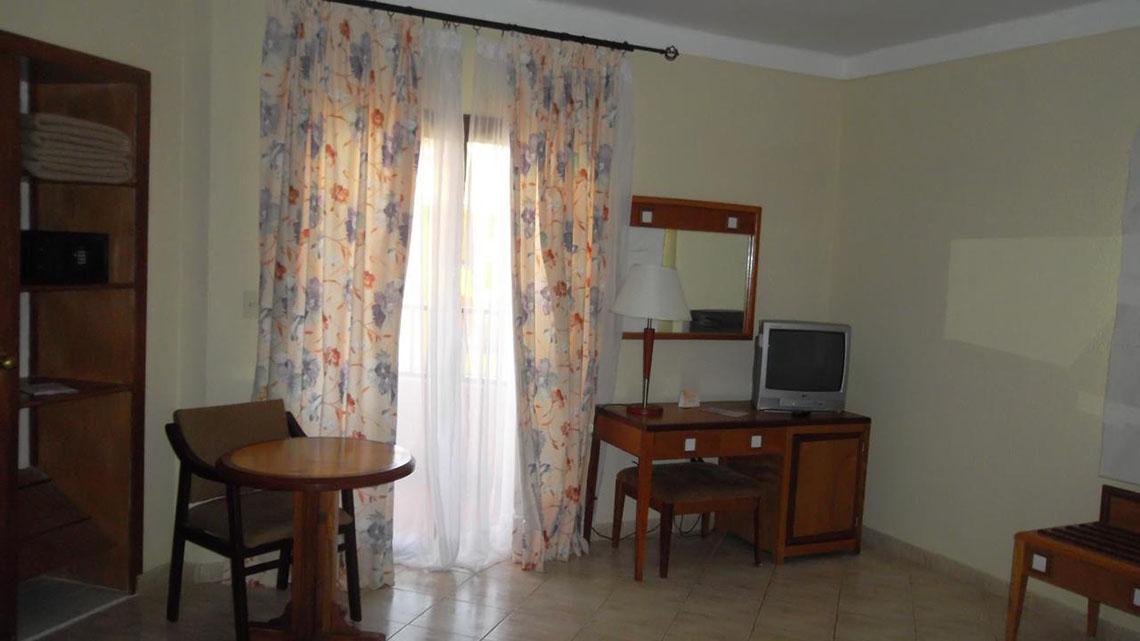 Das Zimmer im ROC Arenas Doradas Hotel mit Tisch, Stuhl, Fernseher und Schreibtisch.