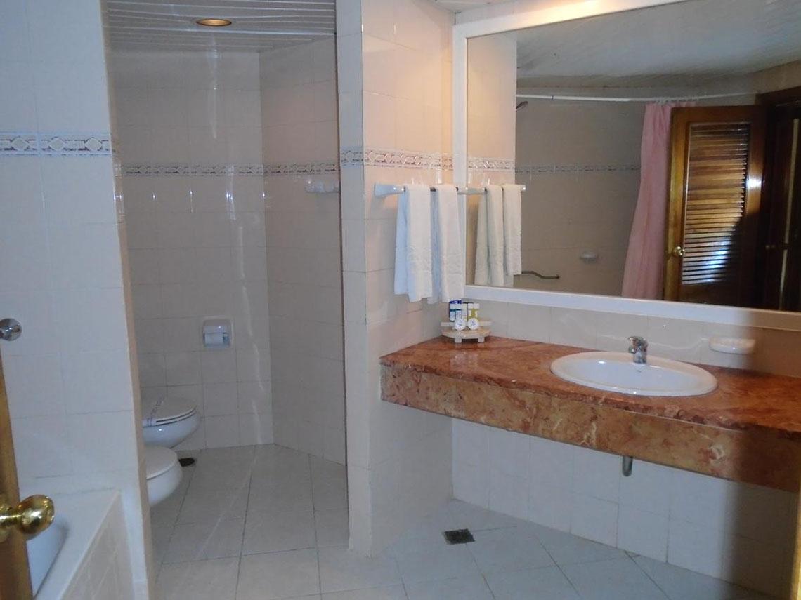 Ein Badezimmer des ROC Arenas Doradas Hotels mit einer Dusche, Toilette, Waschbecken und Spiegel.