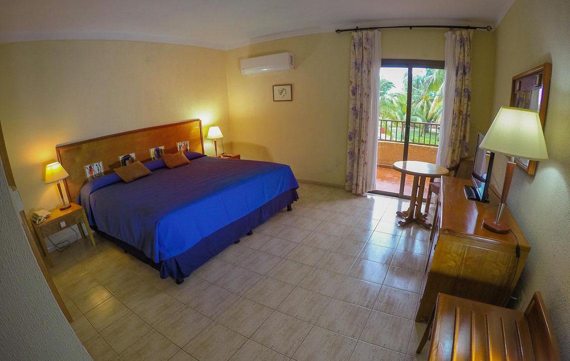Ein Hotelzimmer im ROC Arenas Doradas mit einem großen Bett, Nachttischen, Lampen und einem Balkon.